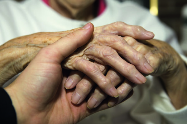 Young man ‘s hand holding senior’s hand Young man 's hand holding senior's hand